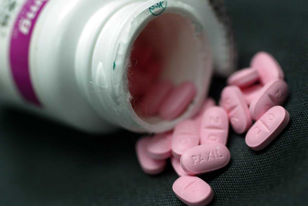 Pink pills spill out of an overturned bottle.