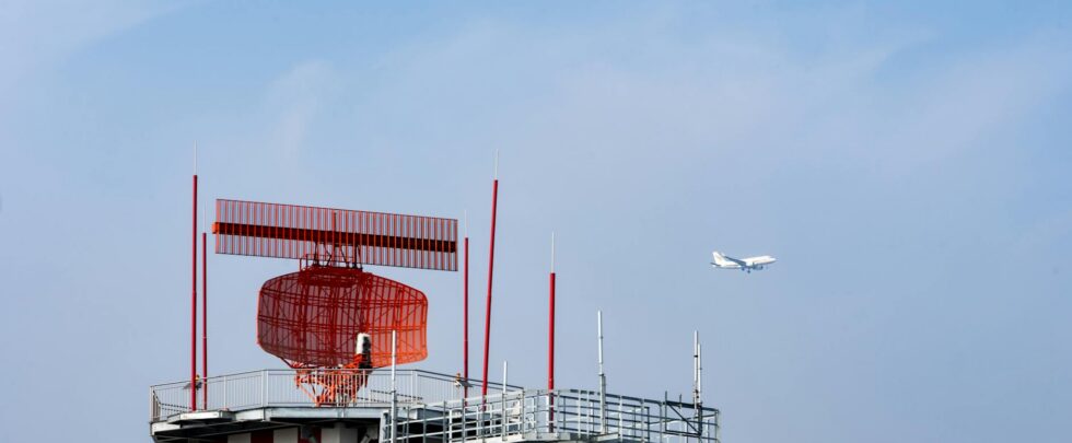 airport radar tower with airplane in sky